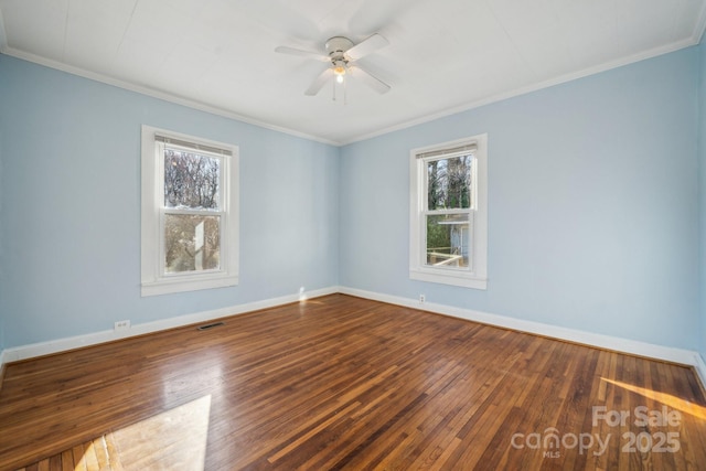 empty room with visible vents, baseboards, wood finished floors, and ornamental molding