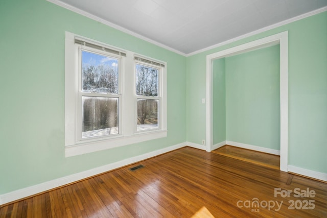 spare room featuring hardwood / wood-style flooring, baseboards, and ornamental molding