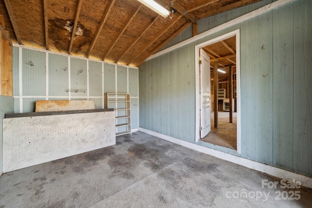 interior space with wood walls, concrete flooring, and lofted ceiling