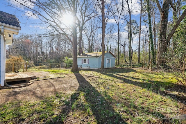 view of yard with a wooden deck, an outbuilding, and fence