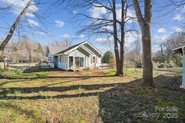 view of side of home featuring a lawn and fence