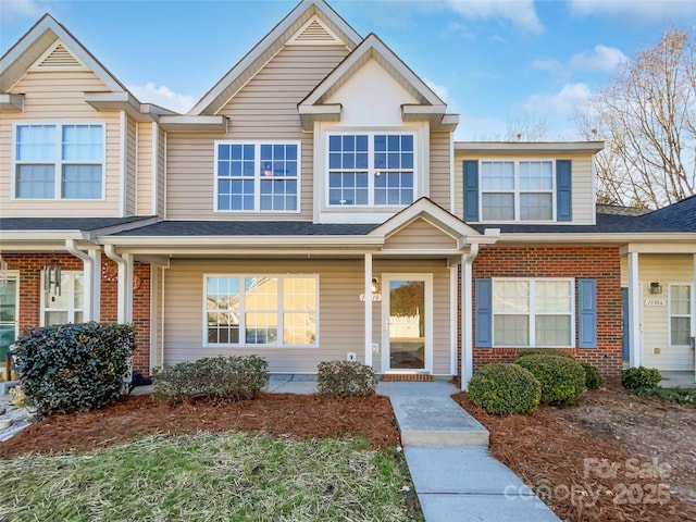 townhome / multi-family property featuring a shingled roof and brick siding