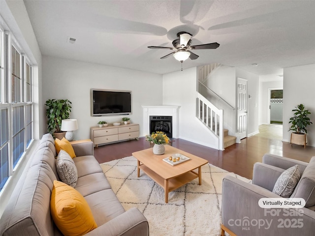 living room featuring visible vents, a ceiling fan, wood finished floors, stairs, and a fireplace