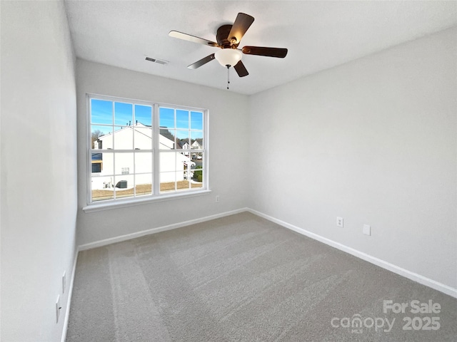 carpeted spare room with a ceiling fan, visible vents, and baseboards