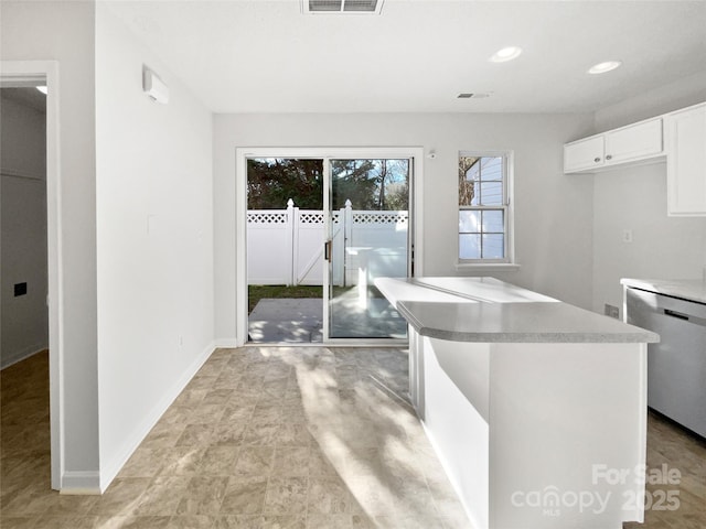 kitchen with baseboards, visible vents, white cabinets, light countertops, and stainless steel dishwasher