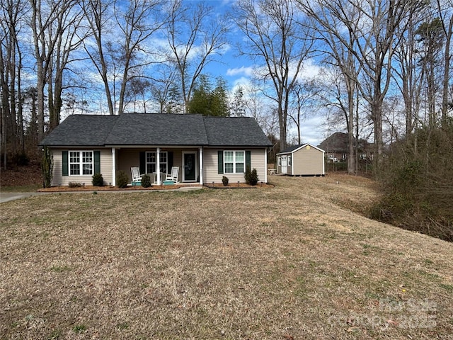 view of front of property with covered porch, a storage shed, an outbuilding, and a front yard