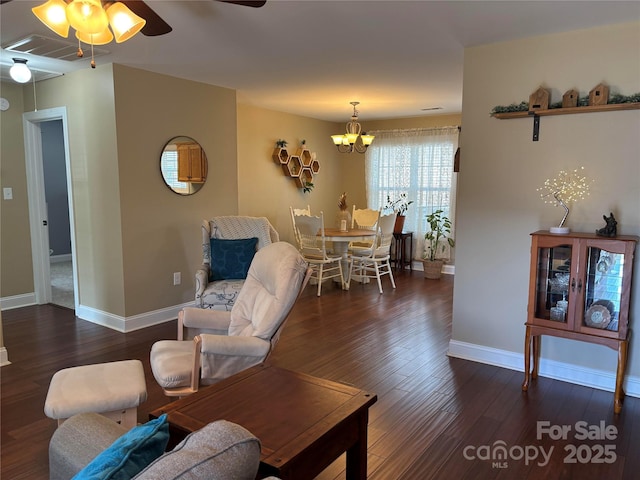 living room featuring ceiling fan with notable chandelier, wood finished floors, visible vents, and baseboards