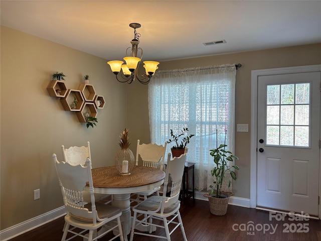 dining space featuring visible vents, a notable chandelier, baseboards, and wood finished floors