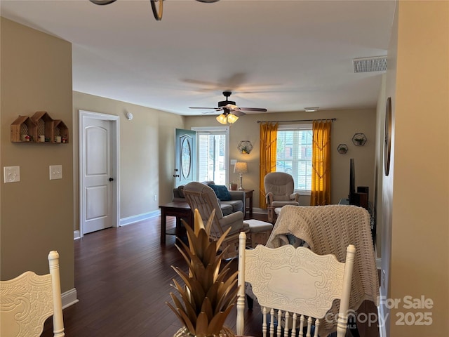 living area featuring dark wood-type flooring, a ceiling fan, visible vents, and baseboards