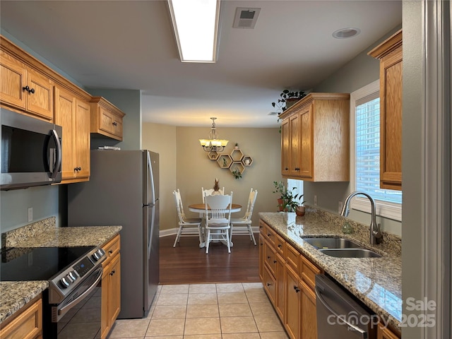 kitchen featuring light tile patterned floors, a sink, visible vents, appliances with stainless steel finishes, and light stone countertops