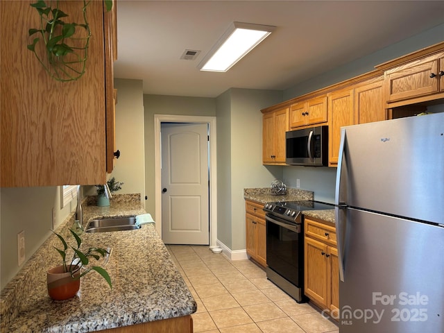 kitchen with light stone counters, stainless steel appliances, visible vents, light tile patterned flooring, and a sink