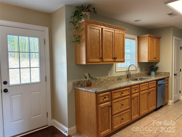 kitchen featuring baseboards, light stone counters, brown cabinets, a sink, and stainless steel dishwasher