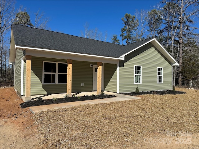 ranch-style home featuring a shingled roof and covered porch