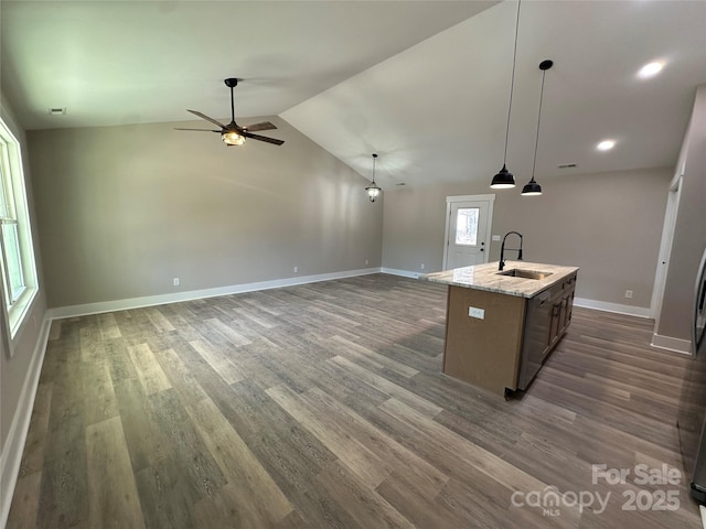 kitchen with dark wood-type flooring, lofted ceiling, a sink, and an island with sink