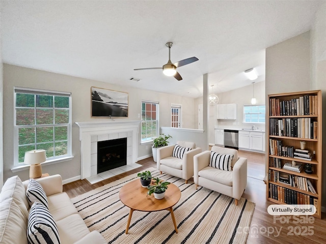 living area featuring light wood-style floors, visible vents, vaulted ceiling, and a wealth of natural light