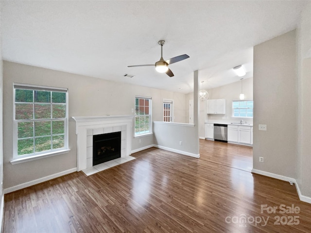 unfurnished living room with visible vents, a fireplace, a sink, and wood finished floors