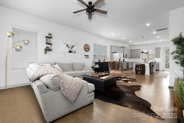 living room featuring wood-type flooring, visible vents, and recessed lighting