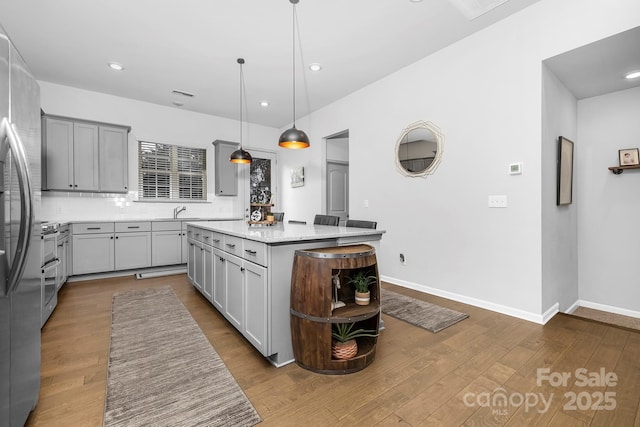 kitchen featuring baseboards, gray cabinets, and dark wood-type flooring