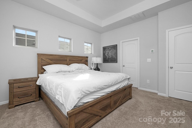 bedroom with carpet, visible vents, baseboards, and a tray ceiling