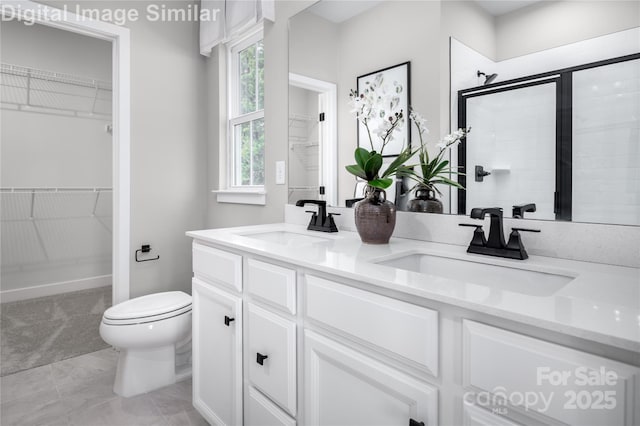 full bathroom featuring a walk in closet, a sink, toilet, and a shower stall