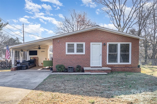 bungalow featuring a front lawn, fence, concrete driveway, brick siding, and ceiling fan