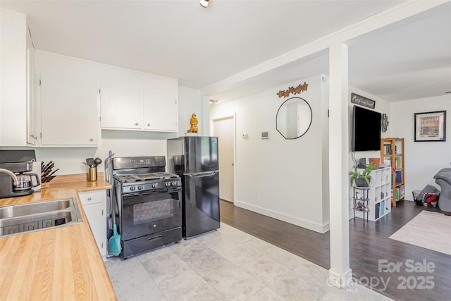 kitchen featuring white cabinets, black appliances, and a sink