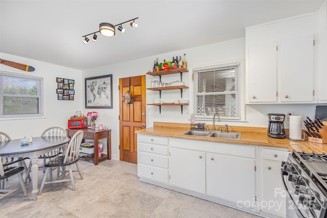 kitchen featuring a sink, range with gas stovetop, and white cabinetry