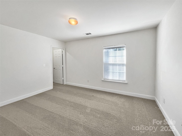 carpeted spare room with visible vents and baseboards