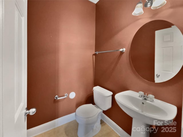 bathroom featuring a sink, toilet, and baseboards