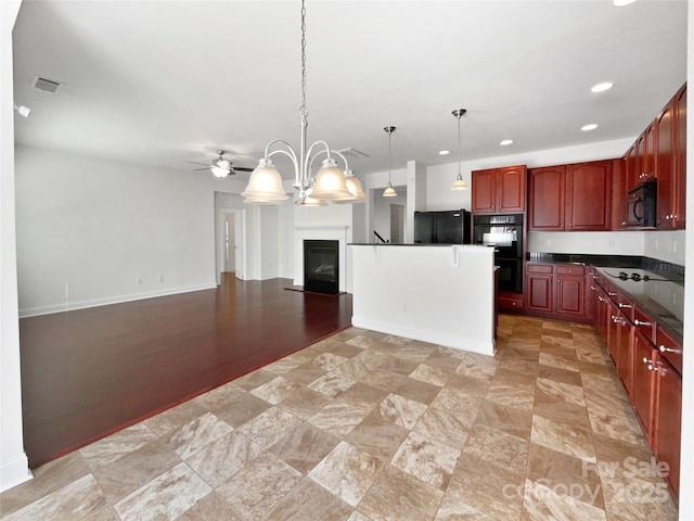 kitchen with dark countertops, visible vents, a glass covered fireplace, open floor plan, and black appliances