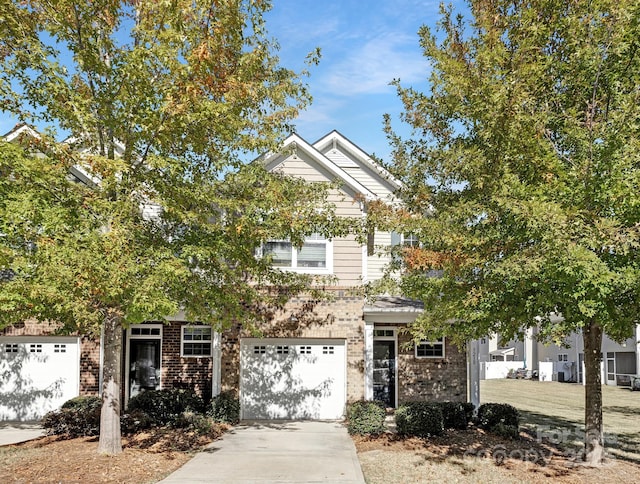 view of front of home with a garage, concrete driveway, and brick siding