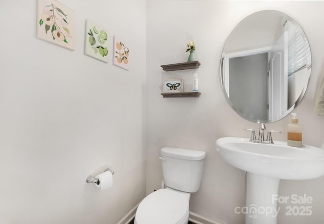 bathroom with toilet, baseboards, and a sink