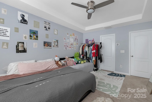 bedroom featuring baseboards, a tray ceiling, ceiling fan, and light colored carpet