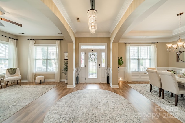 foyer featuring arched walkways, wood finished floors, and a notable chandelier