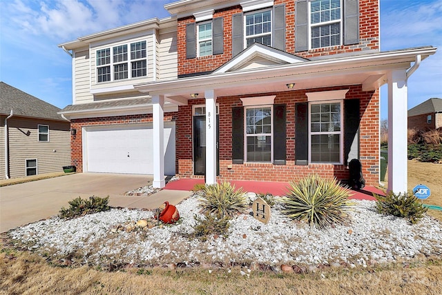 traditional-style house with a garage, concrete driveway, brick siding, and a porch