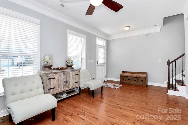 living area featuring a wealth of natural light, stairs, crown molding, and wood finished floors