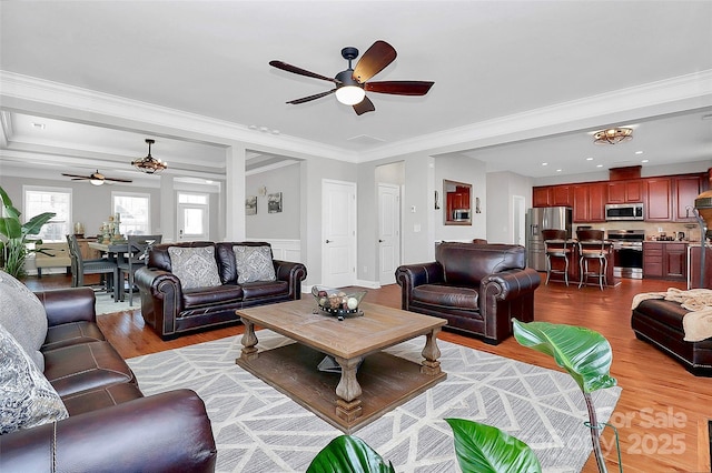 living room featuring ornamental molding, a ceiling fan, and light wood-style floors