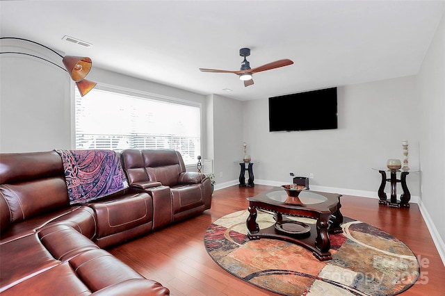 living room featuring a ceiling fan, baseboards, visible vents, and wood finished floors