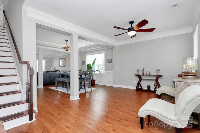 interior space with visible vents, a ceiling fan, stairs, ornamental molding, and light wood-type flooring