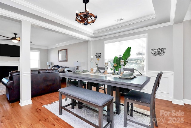 dining space with light wood-type flooring, visible vents, and ornamental molding