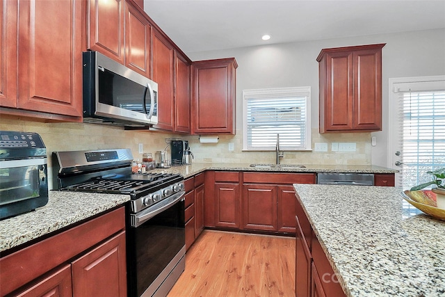 kitchen with stainless steel appliances, a sink, and light stone countertops