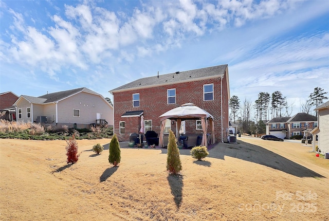 rear view of house with a gazebo, brick siding, a patio, and a residential view