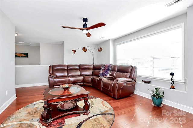 living area with baseboards, visible vents, ceiling fan, and wood finished floors