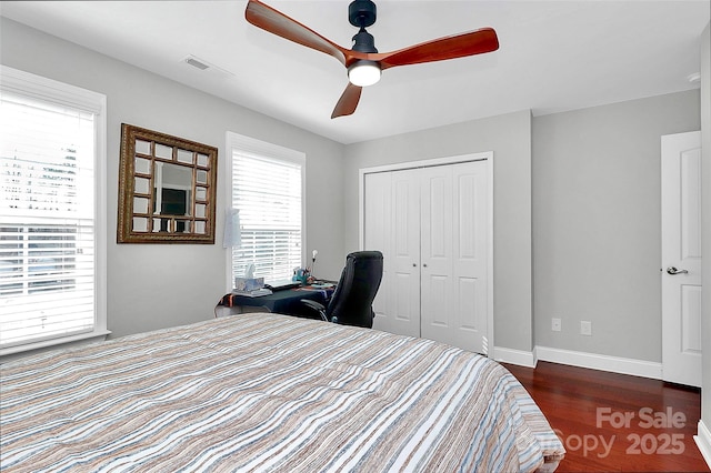 bedroom with a closet, visible vents, dark wood-type flooring, ceiling fan, and baseboards