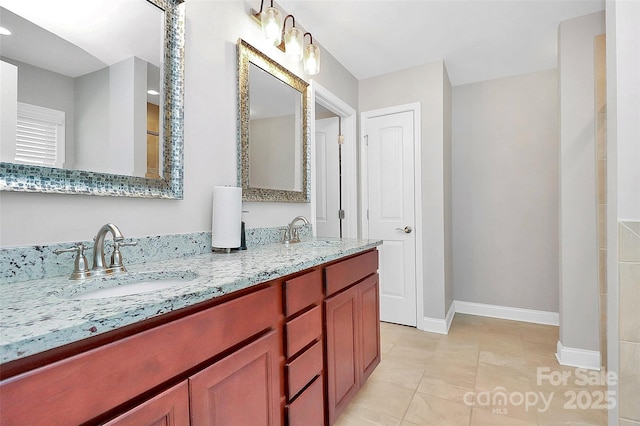 bathroom featuring double vanity, tile patterned floors, a sink, and baseboards