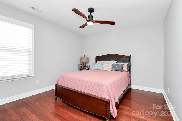 bedroom featuring a ceiling fan, visible vents, baseboards, and wood finished floors