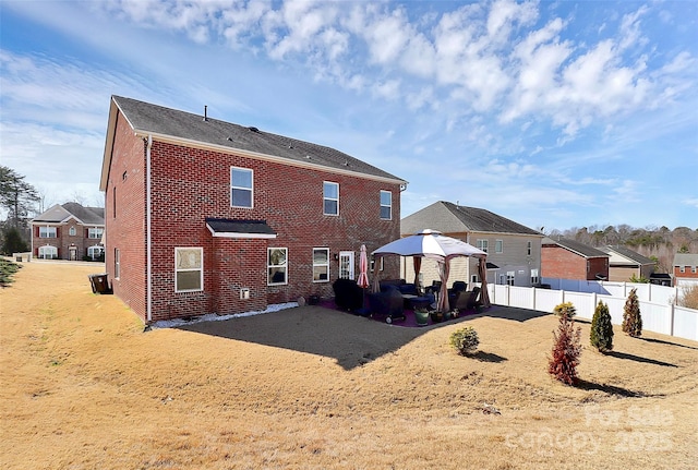 back of property with a gazebo, fence, a patio, and brick siding