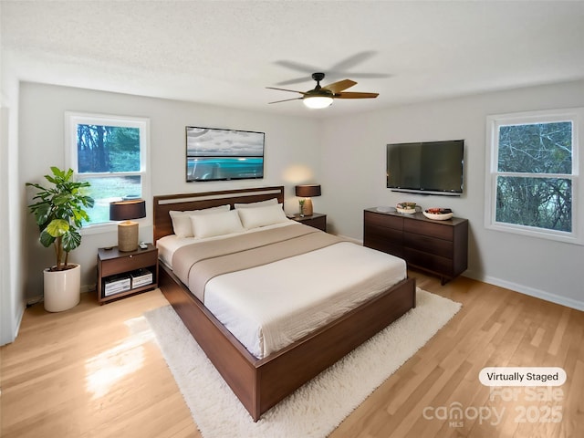 bedroom featuring light wood finished floors, baseboards, and a ceiling fan