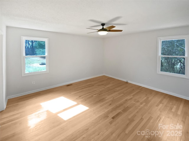 empty room with visible vents, baseboards, a ceiling fan, a textured ceiling, and light wood-type flooring