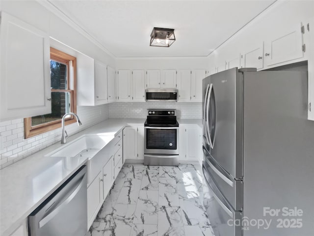 kitchen with marble finish floor, stainless steel appliances, tasteful backsplash, light countertops, and a sink